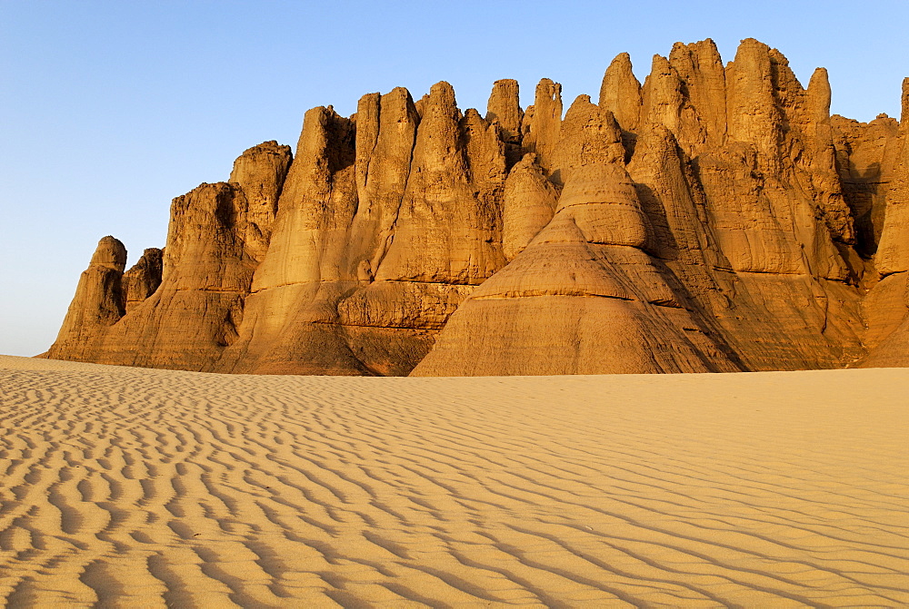 Eroded rock formations rising out of desert sand dunes, ripples in Tin Akachaker, Tassili du Hoggar, Wilaya Tamanrasset, Sahara Desert, Algeria, North Africa