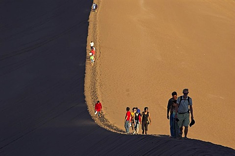 People on a sand dune in the Moon Valley (Valle de la luna), Atacama desert, northern Chile, South America