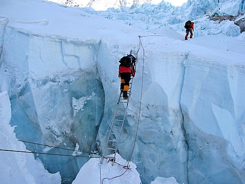 Viennese climber Geri Winkler on a ladder overcoming a crevasse of Khumbu Icefall, ca.5600 m, Mount Everest, Himalaya, Nepal