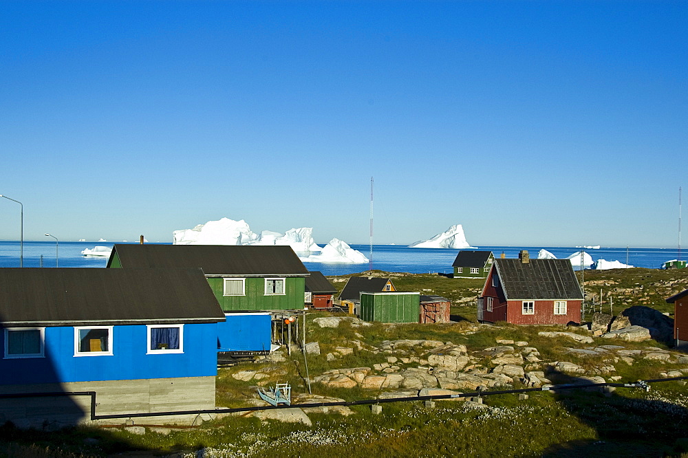 Wooden harbour houses in front of icebergs, Qeqertarsuaq, Disko Island, Disko Bay, Greenland, Arctic