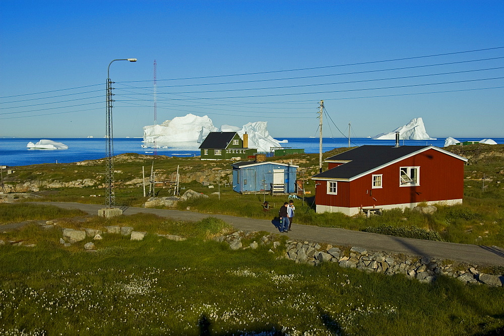 Inuit in front of a wooden house, icebergs visible at back, Qeqertarsuaq, Disko Island, Disko Bay, Greenland, Arctic