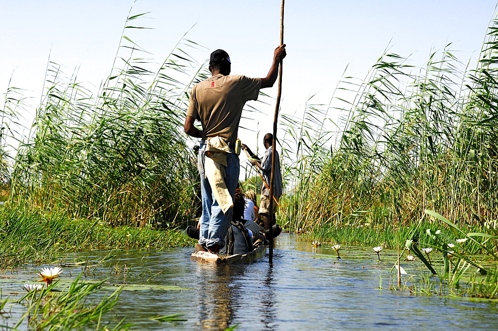 Locals in Mokoro dugoutboat on a tourist excursion in the Okavango Delta, Botswana