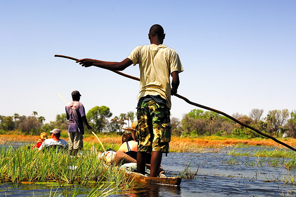 Locals in Mokoro dugoutboat on a tourist excursion in the Okavango Delta, Botswana