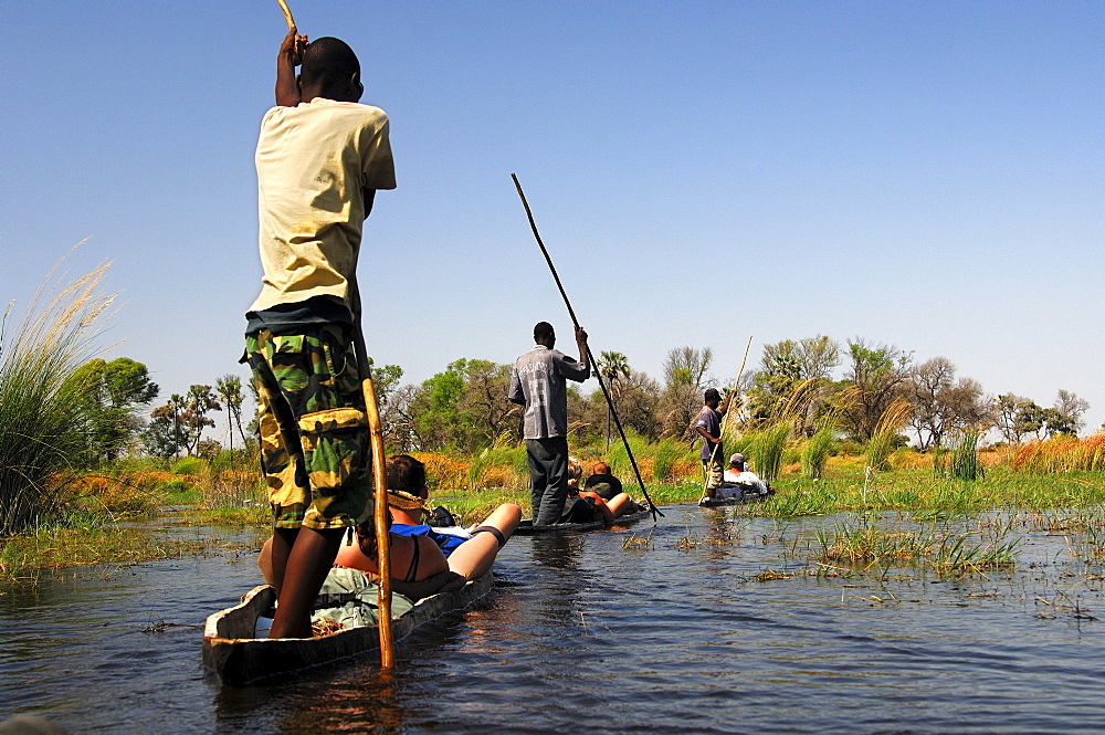 Locals in Mokoro dugoutboat on a tourist excursion in the Okavango Delta, Botswana