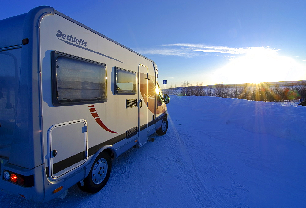 Camper driving through wintry landscape at sunset, Finnmark, Norway, Scandinavia