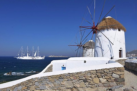 Windmills and white sailboat, bark, four-masted sailing ship, landmark of Mykonos Island, Cyclades, Greece, Europe