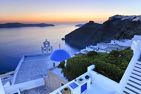 Stairway leading down to a white Greek church with a blue dome and a bell tower at sunset, Firostefani, Santorini, Cyclades, Greece, Europe