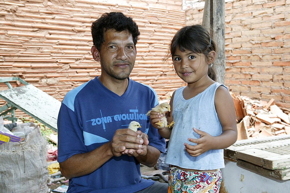 Guarani father and daughter with fledgling in his hand, in the poor area of Chacarita, Asuncion, Paraguay, South America