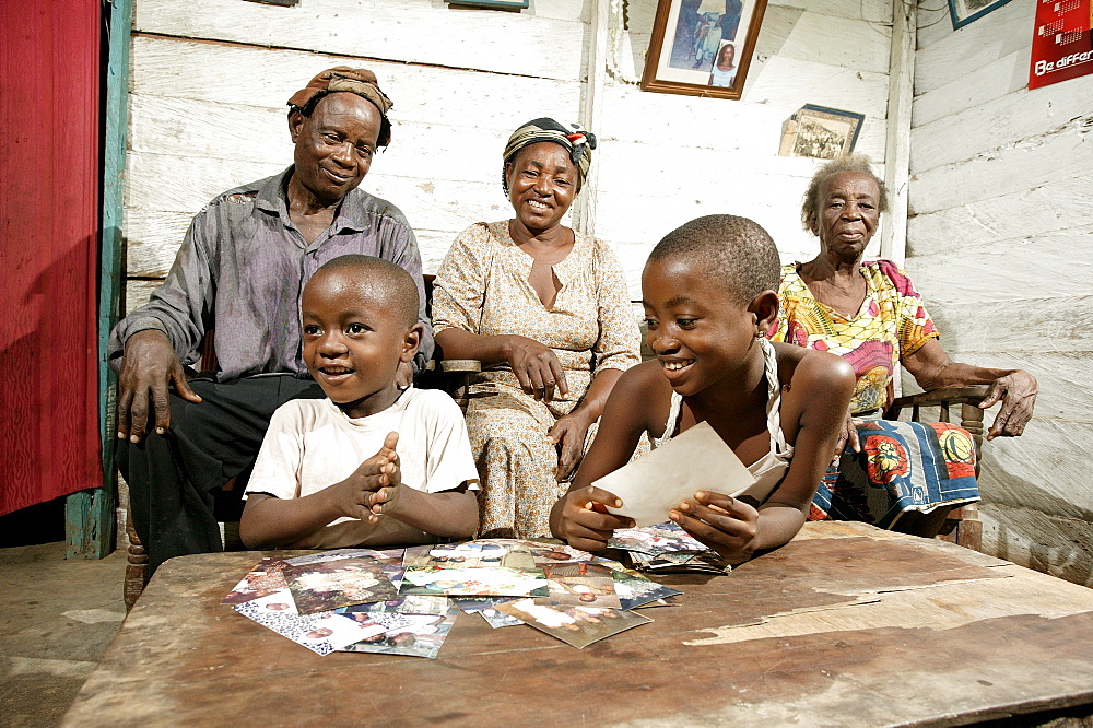 Grandparents and their grandchildren, AIDS orphans, looking at photographs, Cameroon, Africa