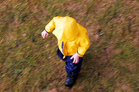 Running kid with yellow rain jacket, from the top