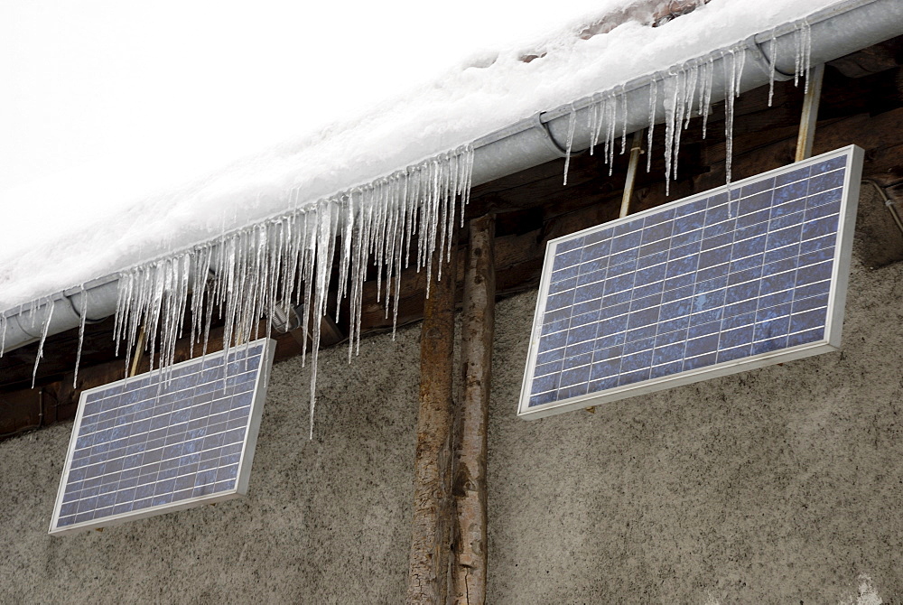 Icicles hanging from raindrainage with solar panels on alpine cottage, Wagner Alm Deutschland