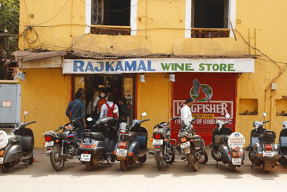 A row of men at a wine store in a street of Panaji or Panjim, Goa, India