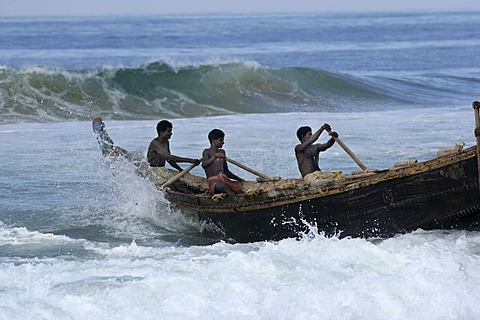 |IND, India, Kerala, Trivandrum : Fishermen at the beach, Malabar coast, south of Trivandrum. Rowing a wooden fishing boat through the surf into the open water. |