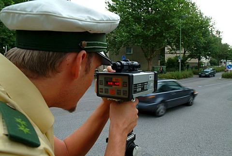 DEU, Germany, Essen: Traffic speed control in a speeding zone of 30 km/h near a school, with a laser measure gun. Daily police life. Officer from a city police station.