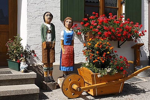 Wooden figures of a couple, wooden barrow in front of a farmhouse in Stoetten am Auerberg, interior view, Allgaeu, Swabia, Bavaria, Germany, Europe