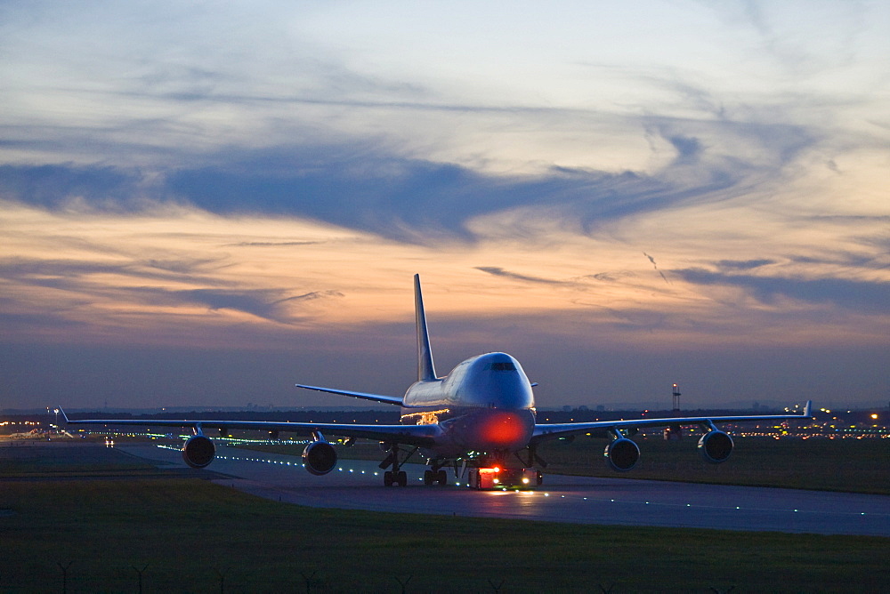 A Boeing 747 is dragged in the evening about the landing field.