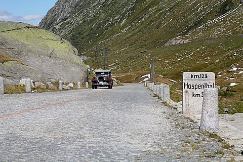 Historic section of cobblestone pavement on the old Gotthard pass route with milestone to Hospental and Oldtimer, Gotthard, Switzerland