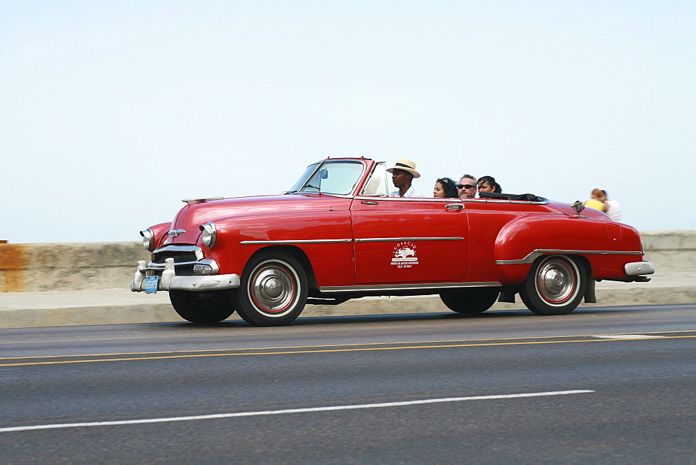 Car driving on Malecon Road alongside Estrecho de la Florida bay in Havana, Cuba, Caribbean, Americas