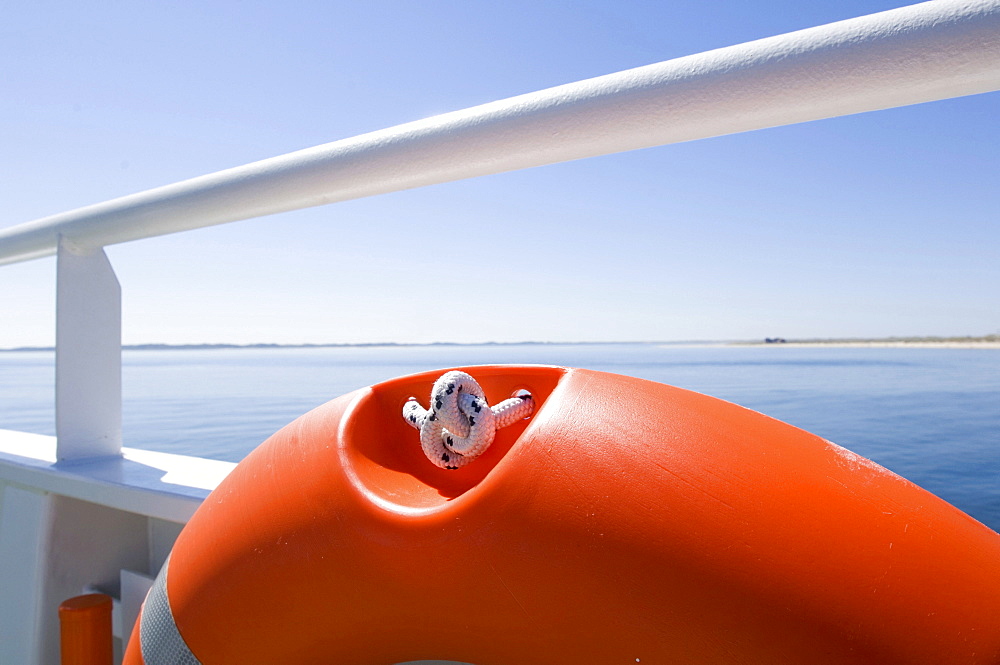 Detail of orange lifebelt on a white rail on a ferry in the North Sea.