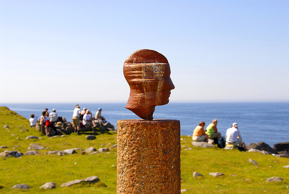 Group of hikers taking a break behind head, art piece designed by artist Markus Raetz, Lofoten, Norway