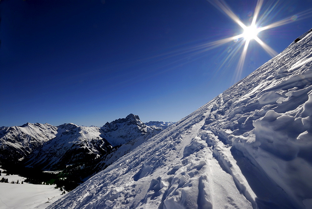 Steep slope (backlit) and a view of the Allgaeu Alps, Baad, Kleinwalsertal, Vorarlberg, Austria, Europe