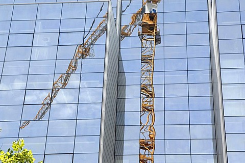 Reflection of a building crane in a modern glass facade