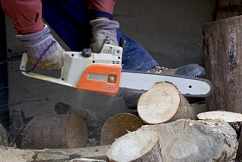 A man sawing pieces of wood with a chainsaw