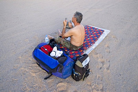 Man shaving his beard in the desert