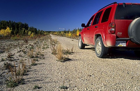 Red fourwheeldrive on a dirt road, Northwest Territories, Canada