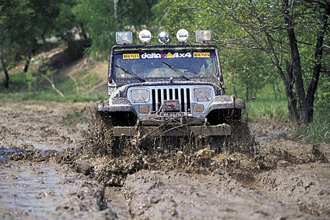 Jeep offroad vehicle are driving with speed through mud