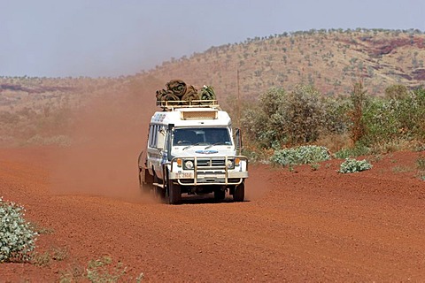 Toyota Landcruiser FJ 75 Arkana safari car with trailer driving on a red road in Karijini National Park Pilbara region western australia WA