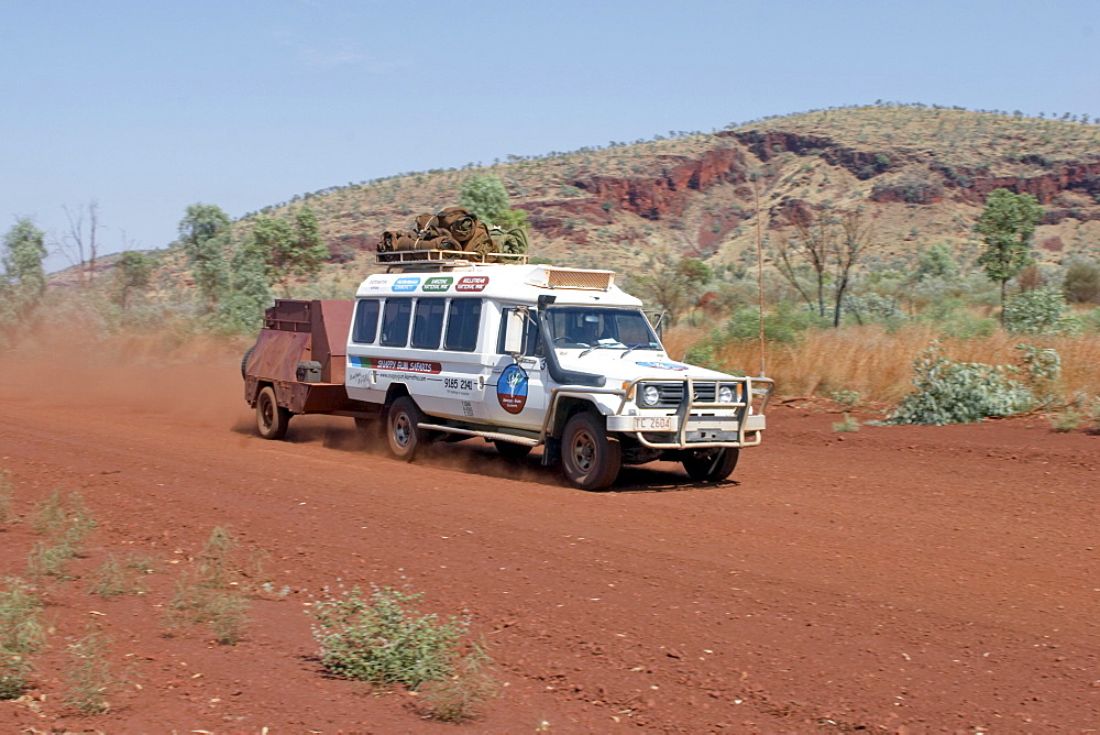 Toyota Landcruiser FJ 75 Arkana safari car with trailer driving on a red road in Karijini National Park Pilbara region western australia WA