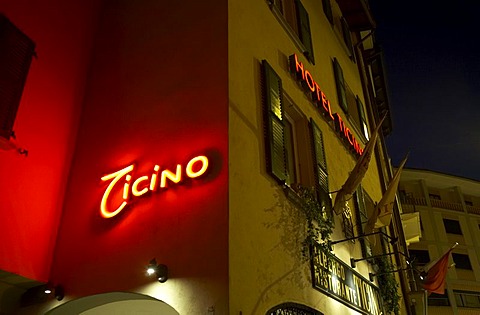 Hotel and restaurant Tessin with lit writing in the old part of town of Lugano in the evening.