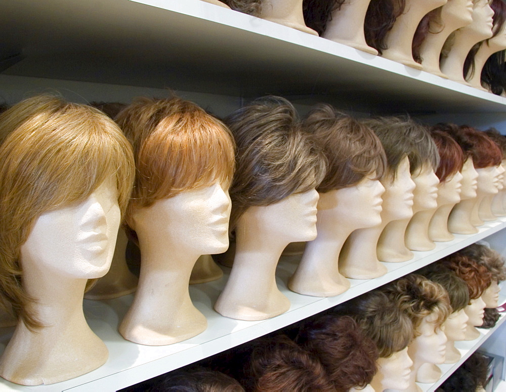 Decorative wigs for ladies placed on styrofoam heads on a rack