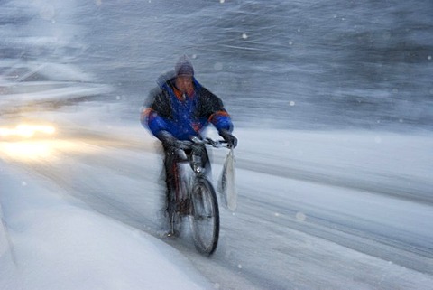 Cyclist at driving snow on snowy road Bavaria Germany