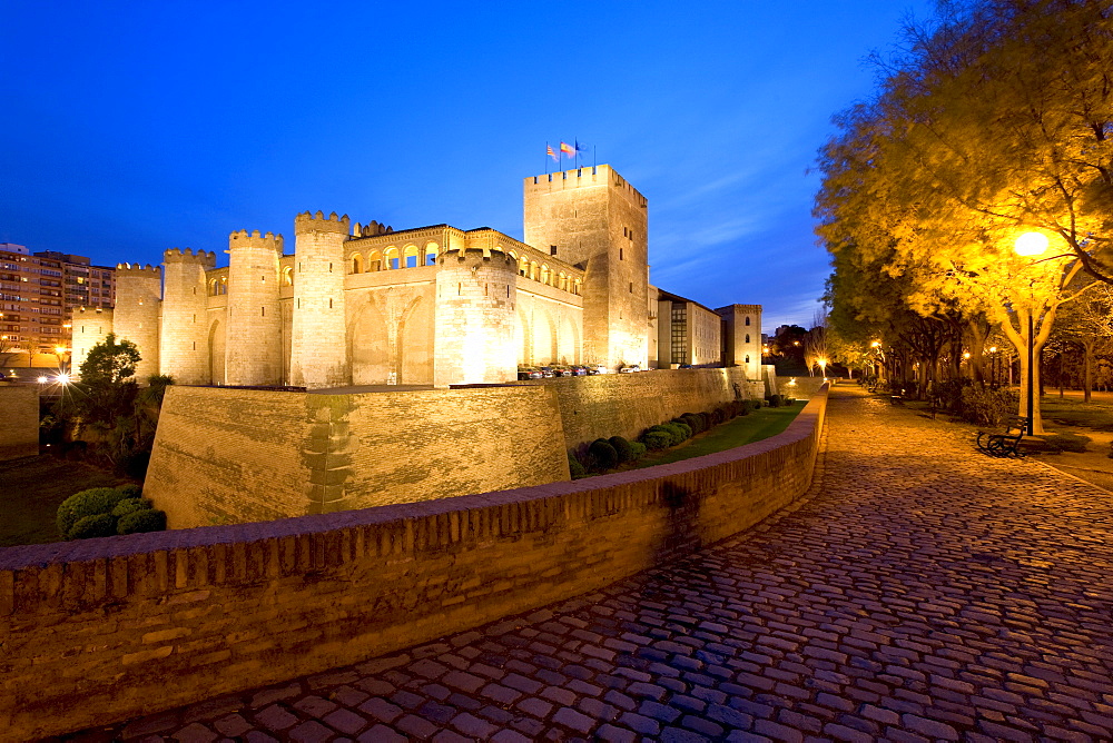 Palacio de Aljaferia palace illuminated at night, flags flying over external wall and towers, Moorish architecture, Zaragoza, Saragossa, Aragon, Spain