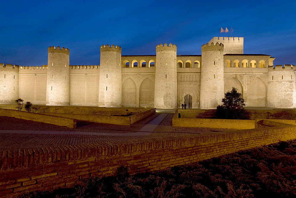 Palacio de Aljaferia palace illuminated at night under floodlights, flags flying over external wall and towers, Moorish architecture, Zaragoza, Saragossa, Aragon, Spain