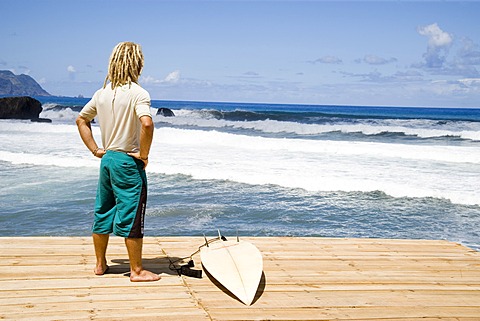 Young surfer in Sao Vincente, Madeira, Portugal waiting for tides looking into the ocean