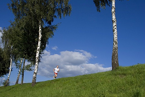 Running woman on a dam in front of blue sky