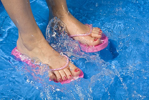 Feet wearing flip-flops in a paddling pool