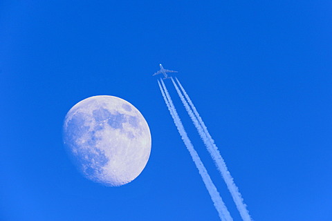 Passenger aircraft with jet trail and moon