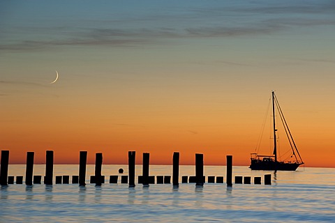 Sailboat, moon and breakwaters in the evening light, sea resort of Zingst, Fischland-Darss-Zingst, Baltic Sea, Mecklenburg, Pomerania, Germany, Europe