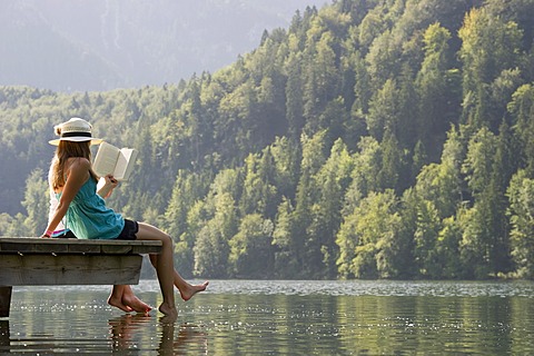 Young women sitting on a landing stage on Lake Schwansee near Fuessen, Allgaeu region, Bavaria, Germany, Europe