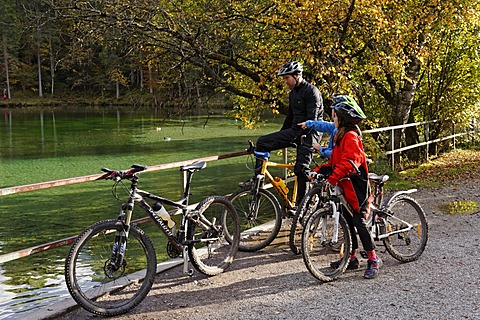 Father and children riding mountain bikes, at Badersee lake in Grainau, Werdenfelser Land, Upper Bavaria, Bavaria, Germany, Europe