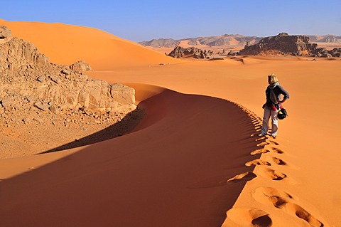 Woman climbing a sanddune at Tin Merzouga, Acacus Mountains or Tadrart Acacus range, Tassili n'Ajjer National Park, Unesco World Heritage Site, Algeria, Sahara, North Africa