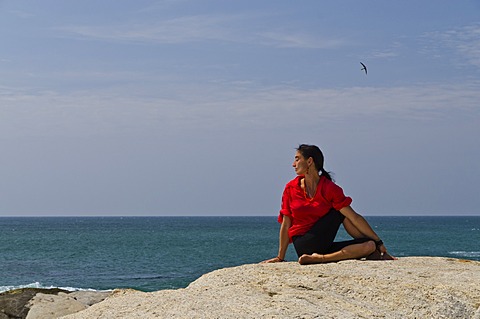 Woman in a yoga position, Ardha Matsyendrasana, by the sea in Kanyakumari, Tamil Nadu, India, Asia