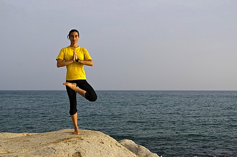 Woman in a yoga position, Vrikshasana, by the sea in Kanyakumari, Tamil Nadu, India, Asia