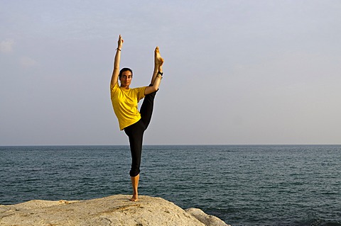 Woman in a yoga position, Anjaneyasana, by the sea in Kanyakumari, Tamil Nadu, India, Asia