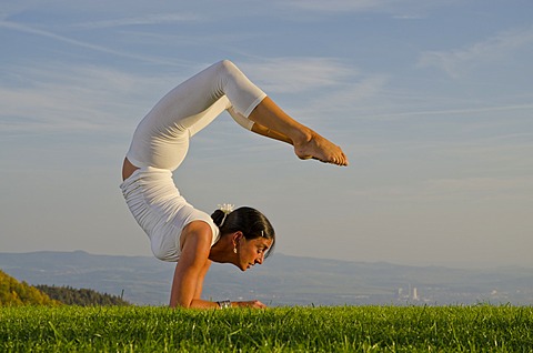 Young woman practising Hatha yoga outdoors, showing the pose vrischikasana, scorpion pose, Nove Mesto, Okres Teplice, Czech Republic, Europe