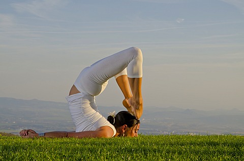 Young woman practising Hatha yoga outdoors, showing the pose poorna shalabhasana, full locust, Nove Mesto, Okres Teplice, Czech Republik, Europe